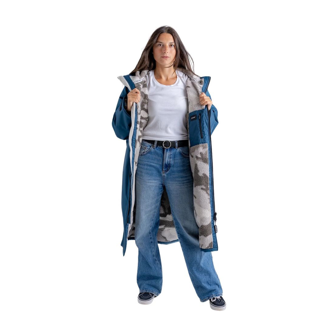 Woman wearing a blue coat over a white shirt and jeans on a white background