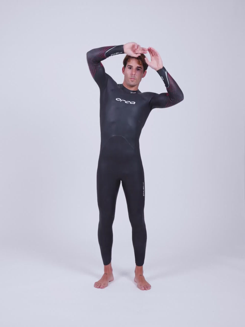 Male model demonstrating a black Orca Athlex Float V2 Triathlon Swimming Mens Wetsuit with red detailing on the sleeves.