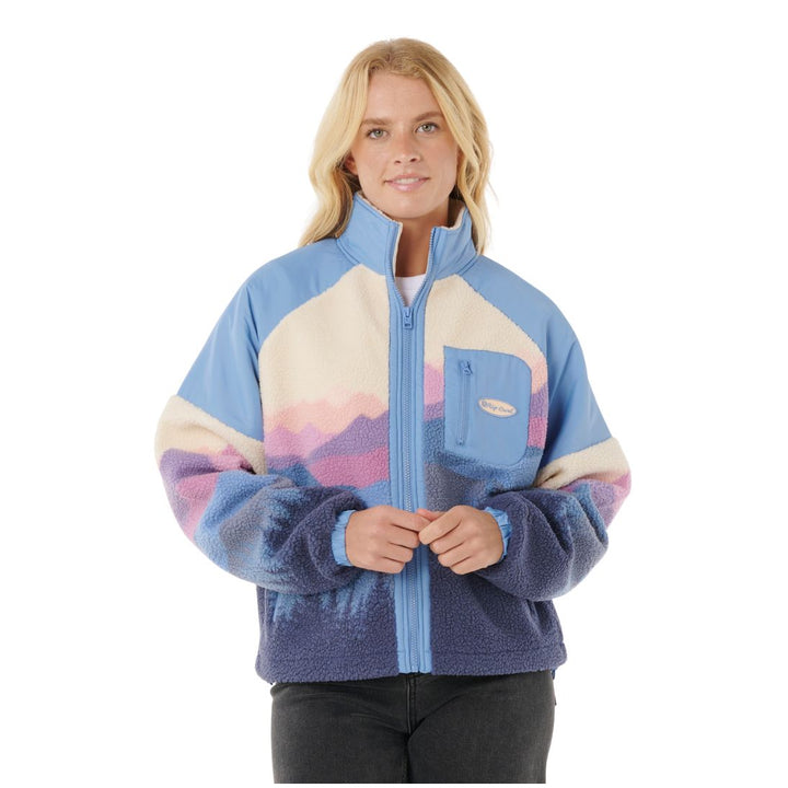 Woman wearing a colorful fleece jacket with a mountain design on a white background