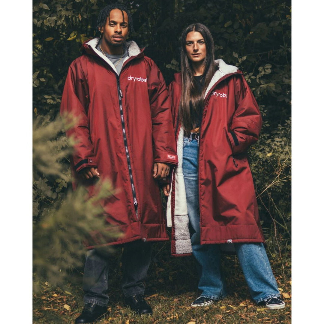 Two people wearing red raincoats standing outdoors in a natural setting.