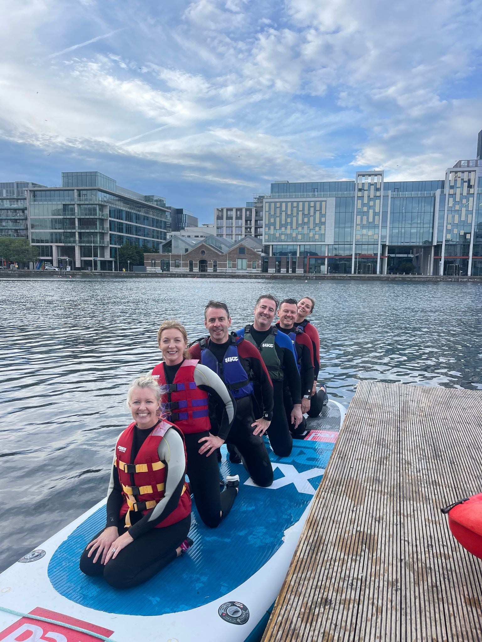 Group of people on a paddleboard with a cityscape in the background